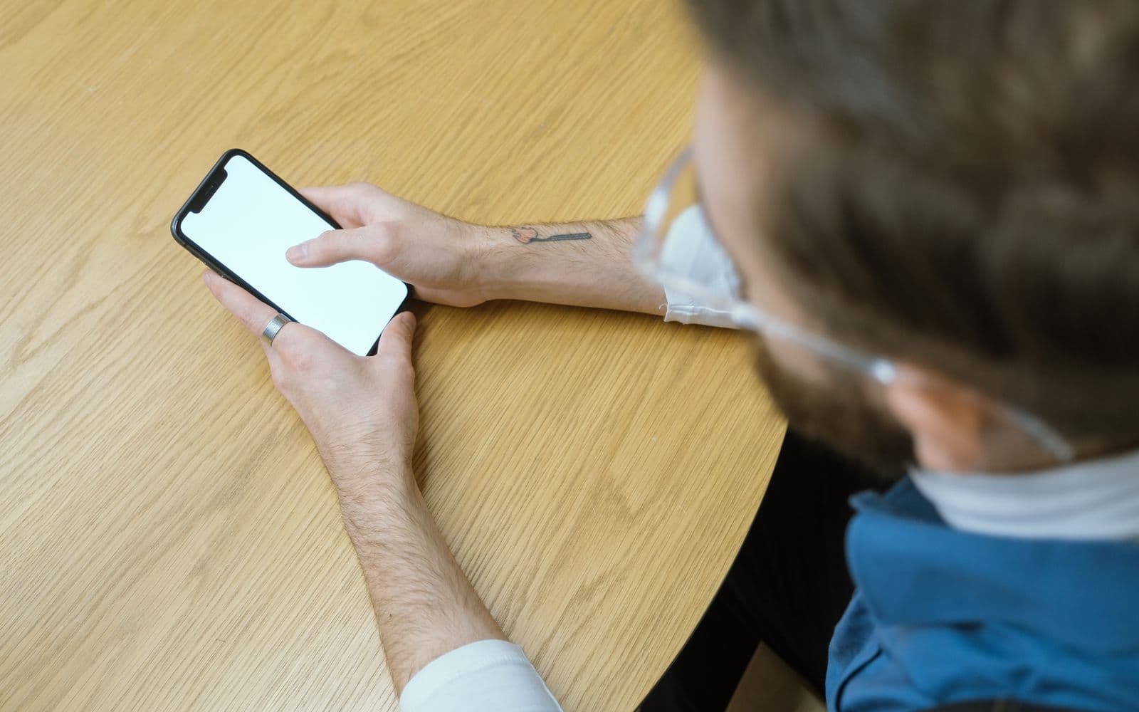 Vue de dessus d'une personne attablée qui consulte l'écran de son téléphone.